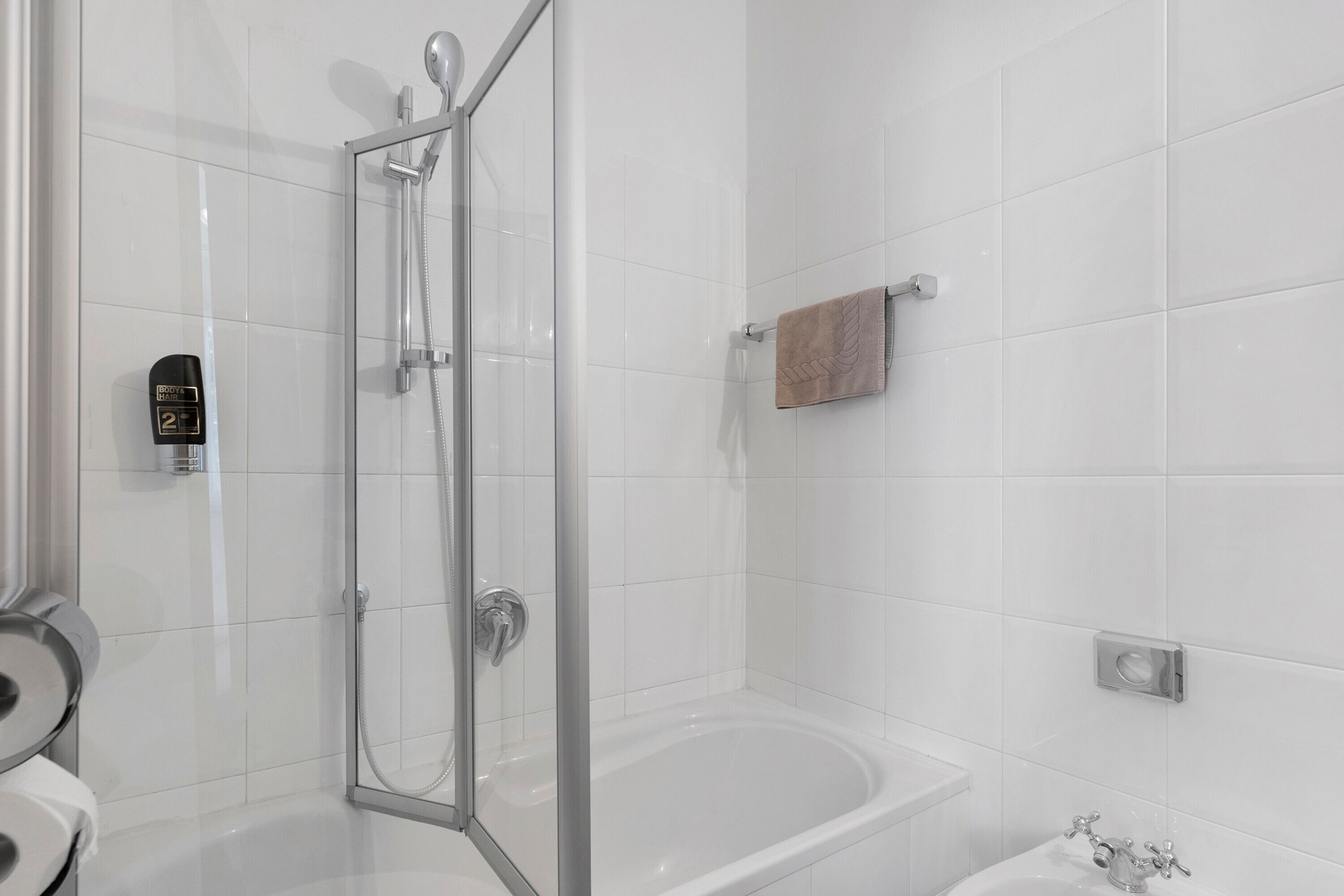 Un bagno moderno con cabina doccia in vetro, vasca e water.