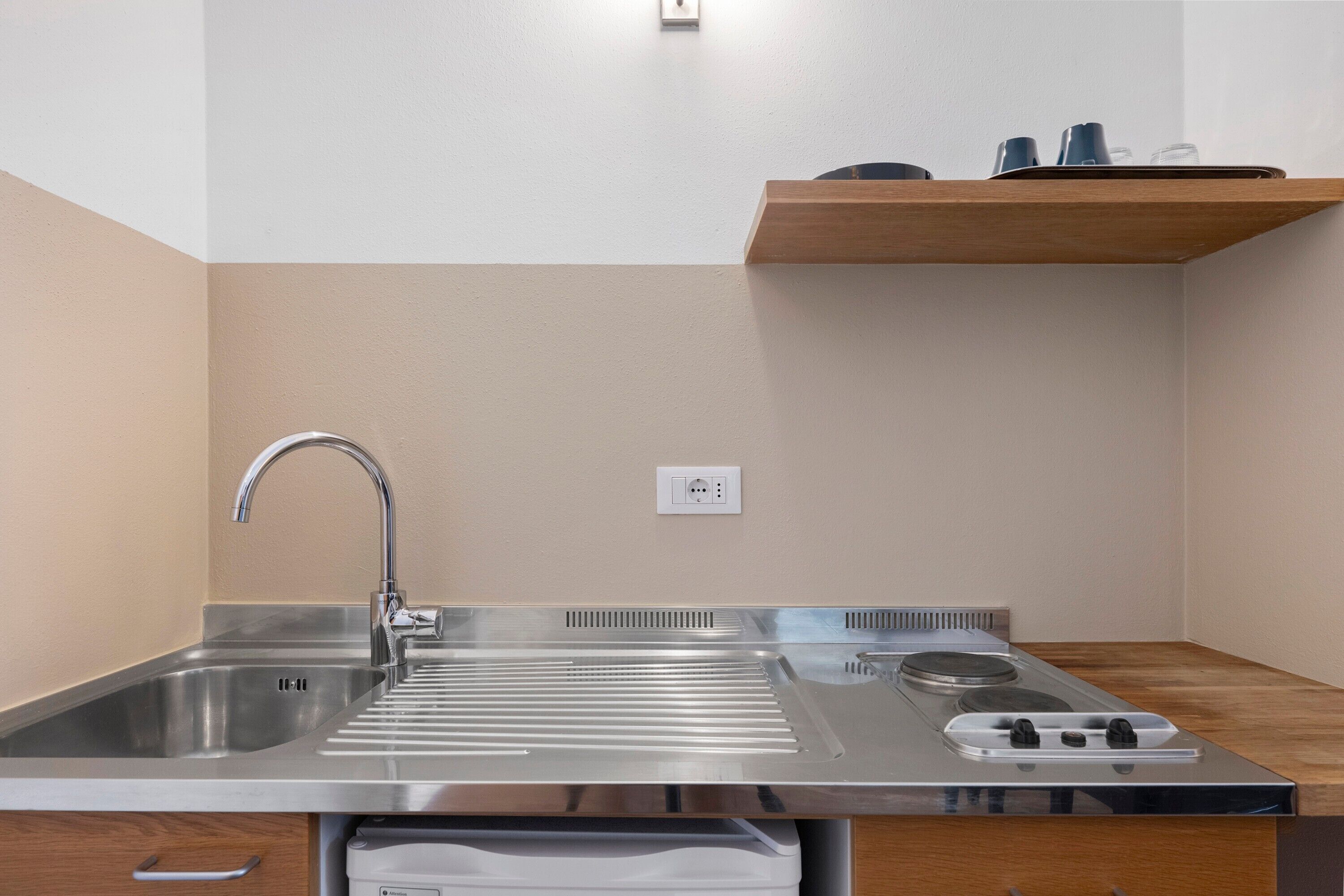 A kitchen with a stainless steel sink, a stove, and a wooden countertop.