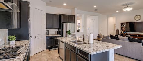 Una cocina moderna con encimeras de granito, electrodomésticos de acero inoxidable y armarios oscuros.