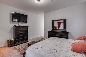 Ein Schlafzimmer mit Bett, Kommode, Fernseher und Spiegel.