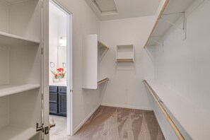 Ein schmaler Flur mit weißen Wänden, einem Teppichboden und einer Tür zu einem Badezimmer mit Toilette und Waschbecken.