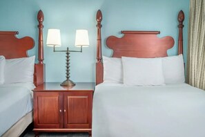Ein Hotelzimmer mit zwei hölzernen Betten, weißer Bettwäsche und einem Nachttisch mit zwei Lampen.