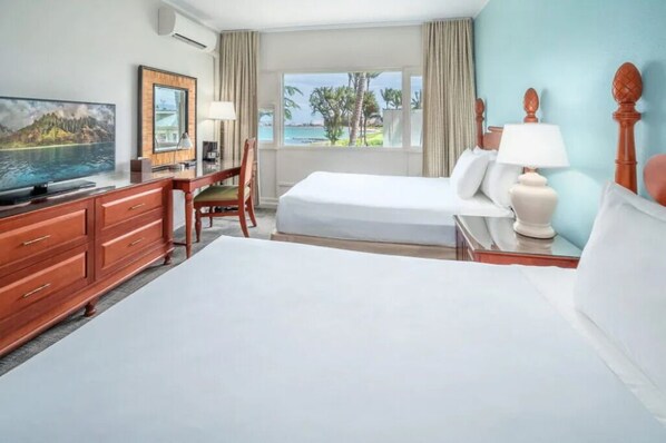 Ein Hotelzimmer mit einem großen Bett, einem Schreibtisch mit Stuhl, einem Fernseher und Blick auf den Ozean.