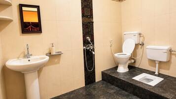 Un baño con lavamanos pedestal, inodoro y ducha.