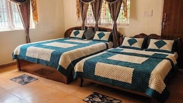 Una habitación con dos camas, cada una con cubrecama acolchado, cabecero de madera y ventana con cortinas.