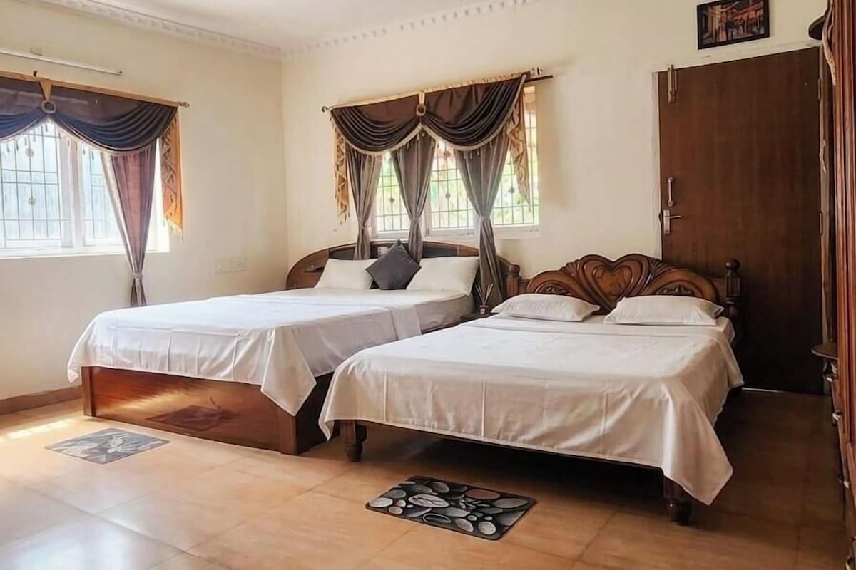A room with two beds, a wooden wardrobe, and a door.