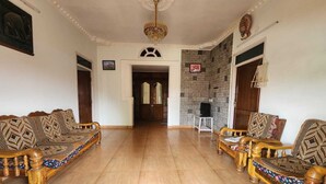 A spacious living room with a high ceiling, a chandelier, and patterned sofas. - Aura Castle (Kodaikanal)