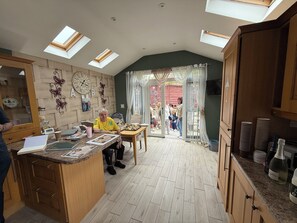 A kitchen with a central island, wooden cabinets, and a dining area with a table and chairs. - BridAj's Place is a full Semi-detached 3 Bed home with parking full of History. (Belfast)