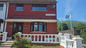 A two-story building with a red facade, a satellite dish, and a sign indicating 'Divismore Crescent.' - BridAj's Place is a full Semi-detached 3 Bed home with parking full of History. (Belfast)