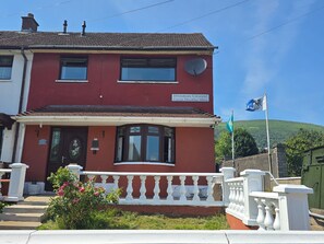 A two-story building with a red facade, a satellite dish, and a sign indicating 'Divismore Crescent.' - BridAj's Place is a full Semi-detached 3 Bed home with parking full of History. (Belfast)