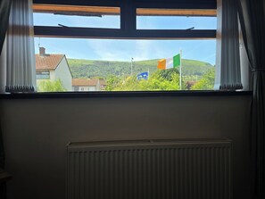 A window with a view of a flag, a radiator, and a building in the background. - BridAj's Place is a full Semi-detached 3 Bed home with parking full of History. (Belfast)