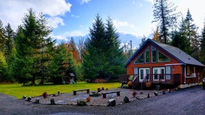 Un chalet avec une façade en bois, un porche et un chemin de pierre menant à l’entrée.