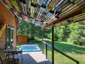 A wooden deck with a hot tub, chairs, and a view of a lush garden. - Wonderful 3-bedroom house with AC in charming Packwood (Packwood)