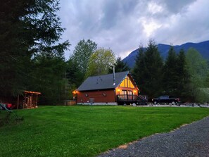 A cabin with a wooden exterior, a porch, and a view of mountains in the background. - Wonderful 3-bedroom house with AC in charming Packwood (Packwood)