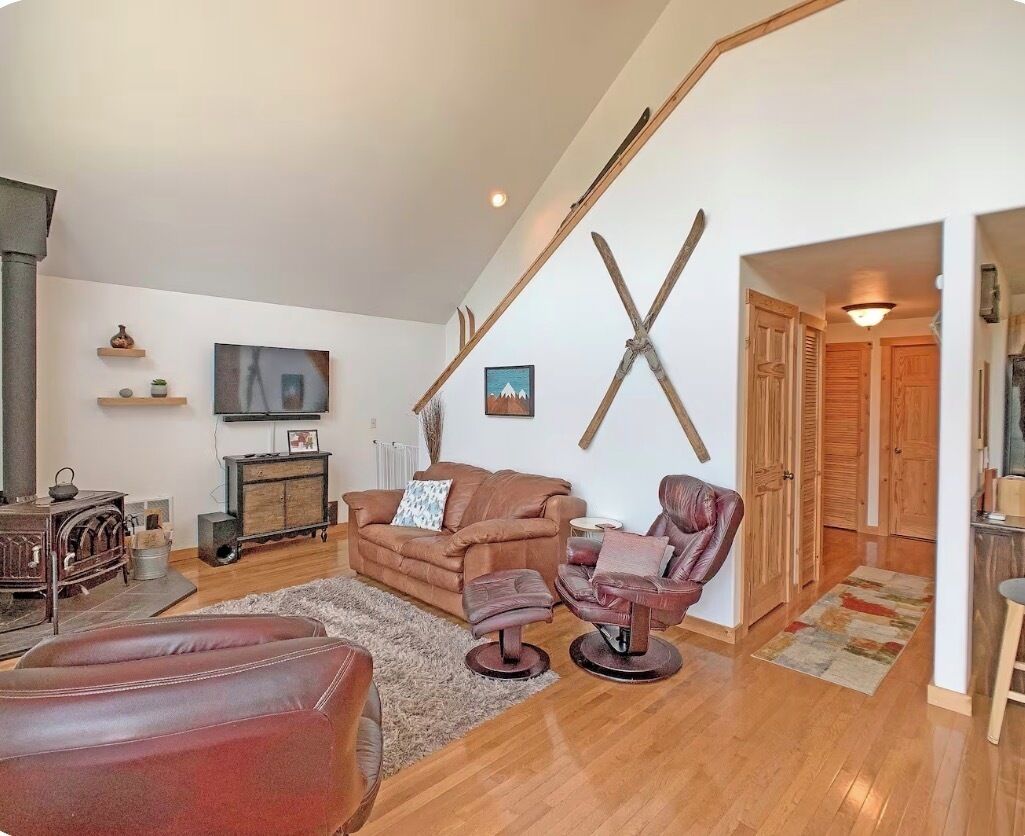 Ein Wohnzimmer mit einem braunen Sofa, einem Ledersessel und einem Fernseher an der Wand.