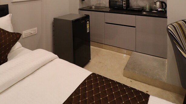 A compact hotel room with a bed, a small kitchenette, and a bathroom. - Exotic Studio Stayz I Artemis Hospital  (Gurugram)