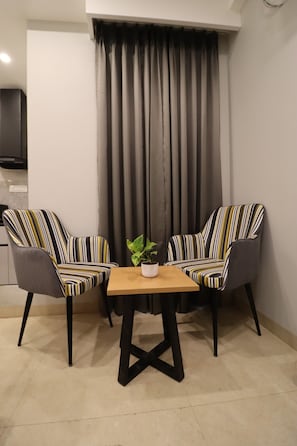 A small room with two striped armchairs, a wooden table, and a potted plant. - Exotic Studio Stayz I Artemis Hospital  (Gurugram)