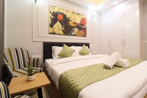Una habitación de hotel con una cama, una silla, una mesa y un cuadro en la pared.
