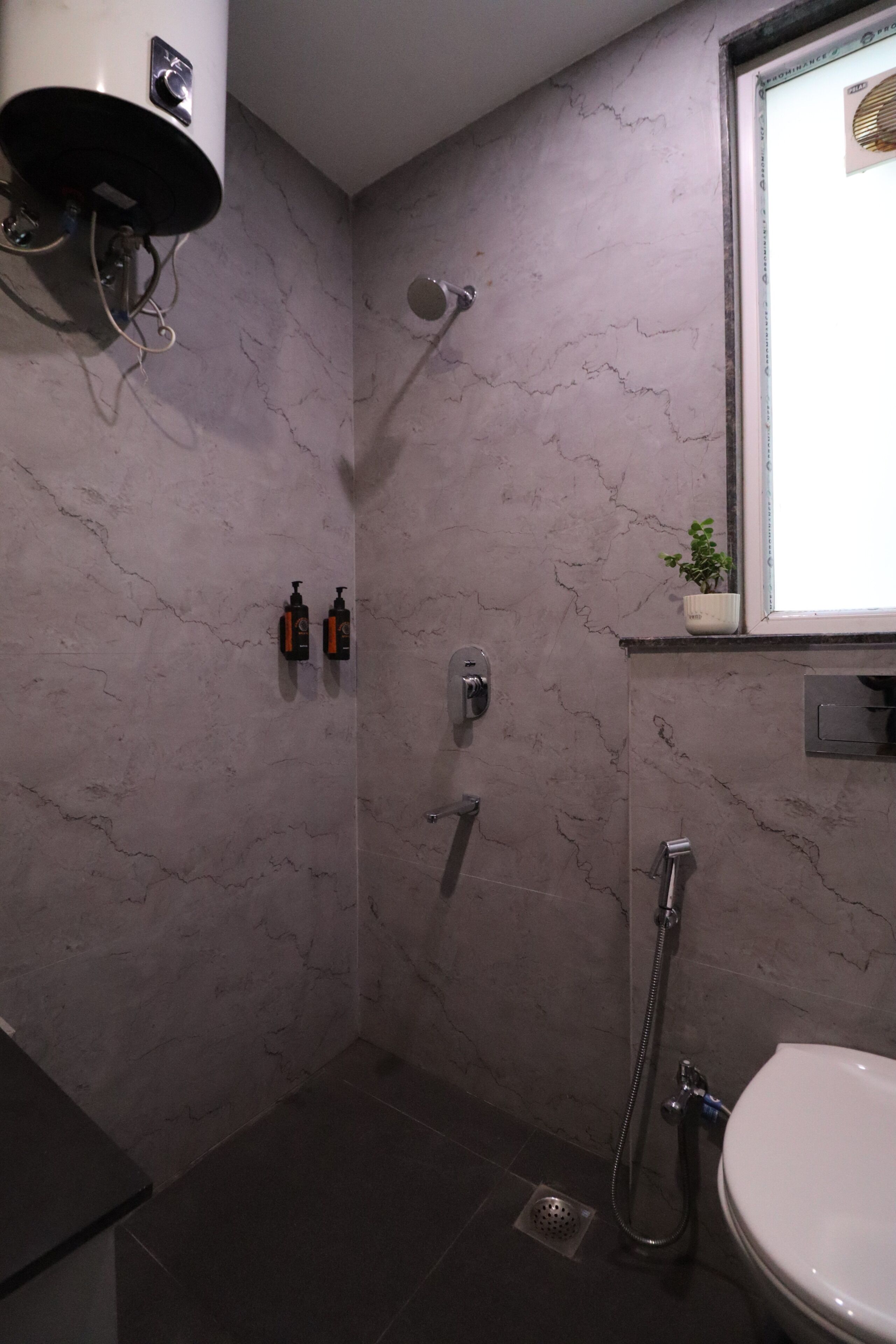 Een badkamer met douche, toilet en wastafel.