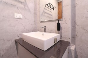 Un baño con un lavabo blanco, un espejo y un dispensador de jabón negro.
