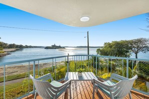 Ein Balkon mit Blick auf einen Fluss, einem Tisch und zwei Stühlen.