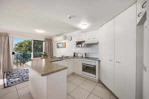 A modern kitchen with white cabinets, a built-in oven, and a microwave. - Charming 2-Bed Coastal Haven Near Esplanade (Maroochydore)
