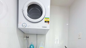 Een kleine wasruimte met een voorlader wasmachine en een droger met bovenlader.