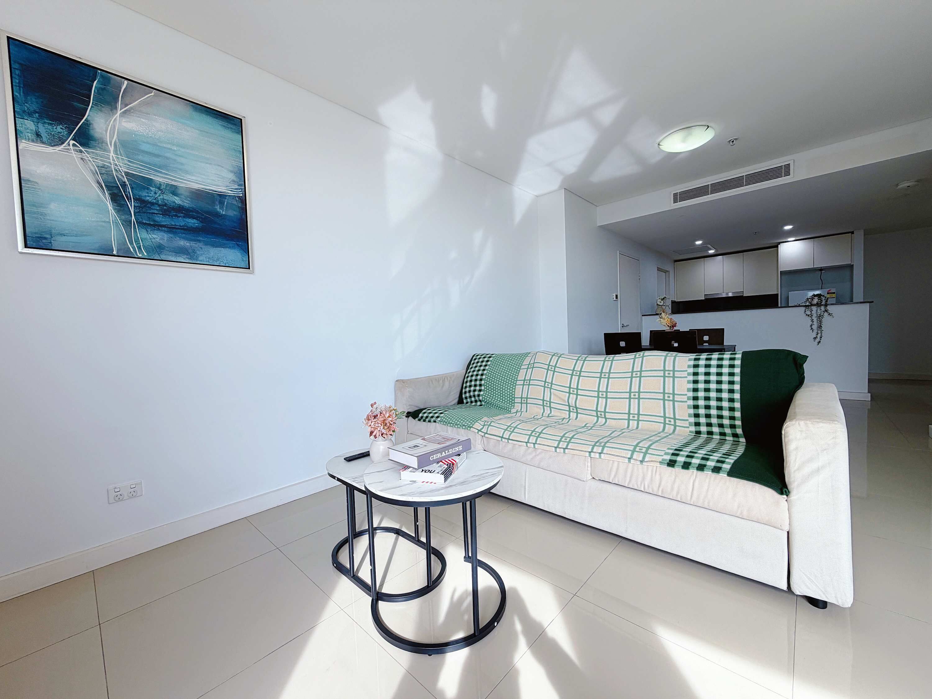 Ein modernes Wohnzimmer mit einer Couch, einem kleinen runden Tisch und einem Bild an der Wand.