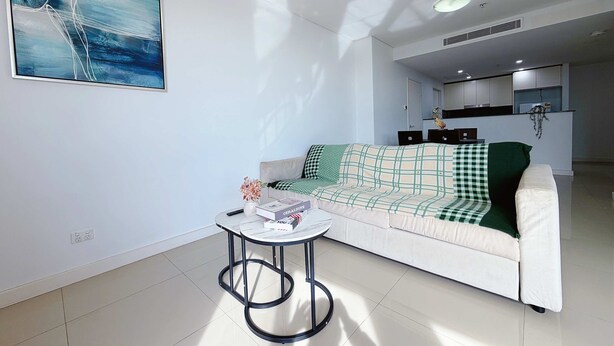 A modern living room with a sofa, a small round table, and a painting on the wall.
