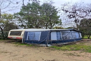 A tent with a covered area, a vehicle, and trees in the background. - Large Tabbert trailer located near the sea in Hyères—secure Beldemé campground (Hyères)