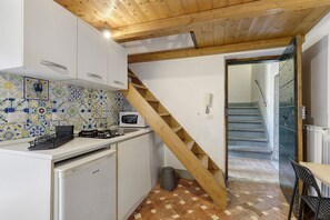 Eine Küche mit einer Holztreppe, weißen Schränken, einer gefliesten Spritzschutzwand und einer Mikrowelle.