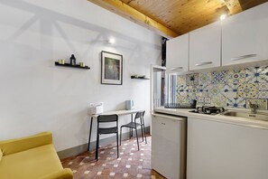 Eine kompakte Küche mit Essbereich, einem gelben Sofa und einer gefliesten Spritzschutzwand.