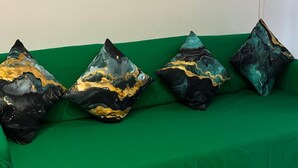 Un sofá verde con cuatro cojines decorativos y dos cuadros enmarcados de rosas en la pared.