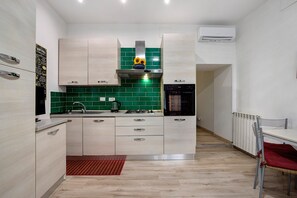 Eine moderne Küche mit hellen Holzschränken, einer grünen Spritzschutzwand und einem eingebauten Backofen.