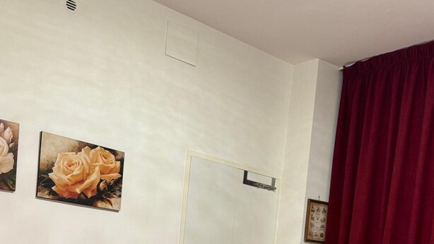 Un dormitorio con cama, puerta y ventana con cortinas.