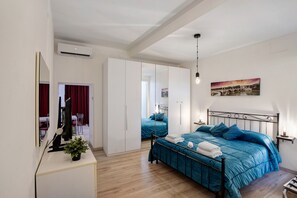 A bedroom with a bed, bedside tables, a mirror, a potted plant, and a painting on the wall. - Suite Colosseo 54 Apartment with Wi-Fi and Air Conditioning (Rome)