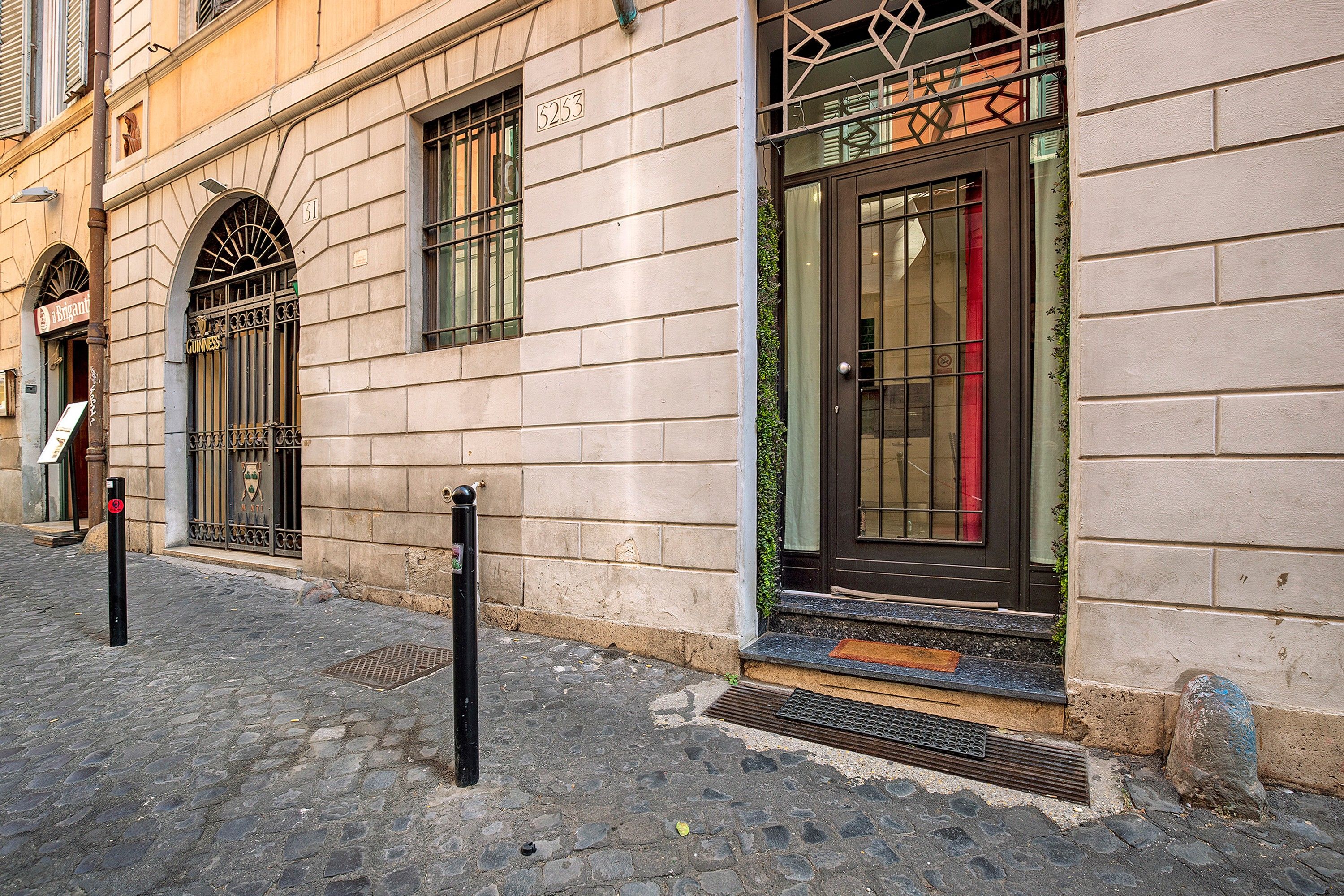 Un bâtiment à la façade en pierre, portant le numéro 5253, avec une grande entrée dotée d’une porte en verre et d’un portail en métal.