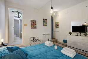 Une chambre à coucher avec un lit, une télévision, une commode et des œuvres d’art accrochées aux murs.