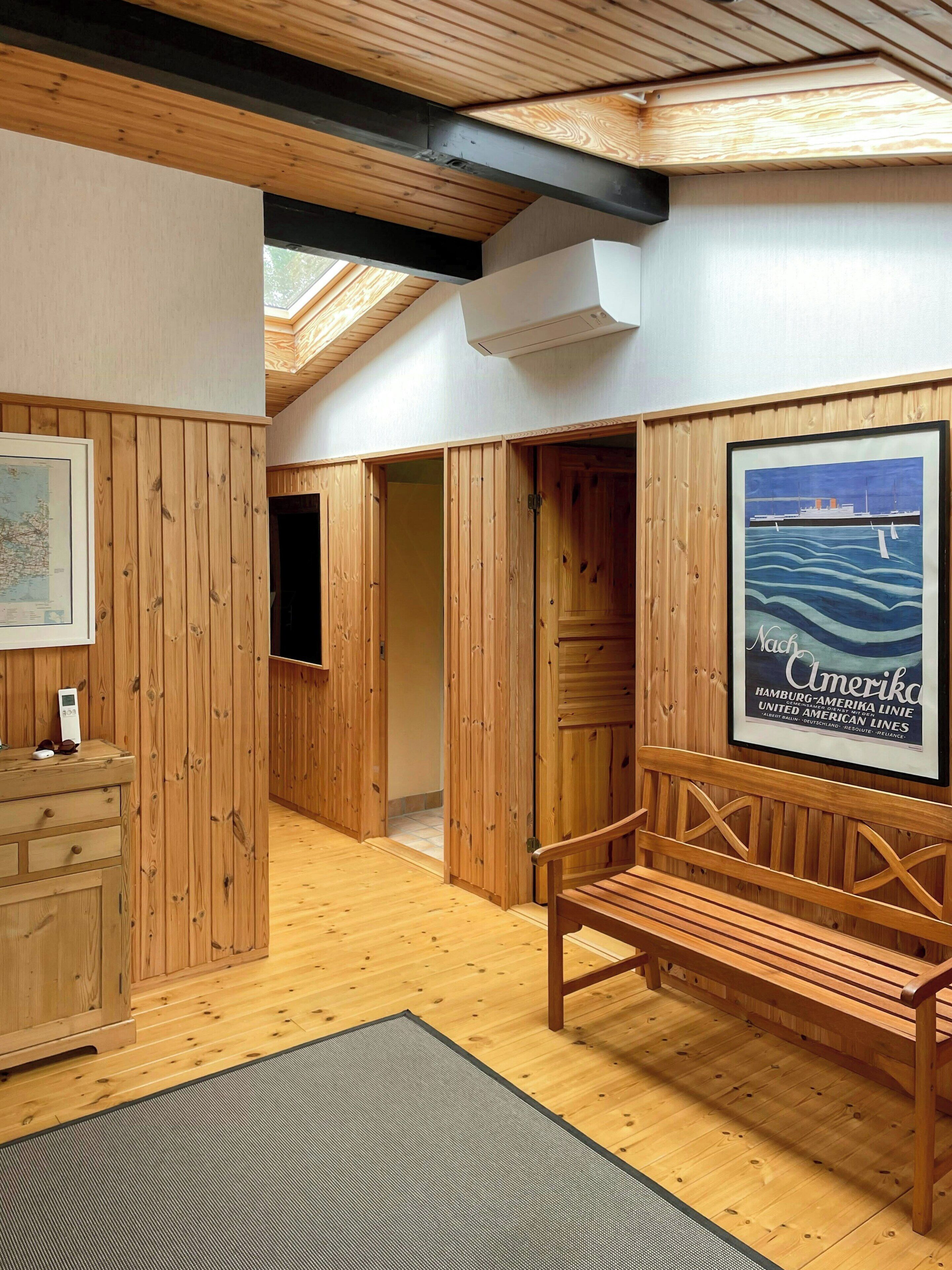 Un intérieur en bois avec un banc, une affiche encadrée et une carte accrochée au mur.