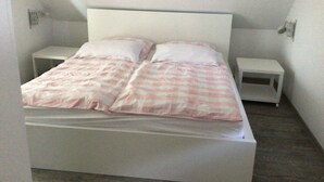 Een eenpersoonsbed met hoofdbord, twee nachtkastjes en een geruit sprei.