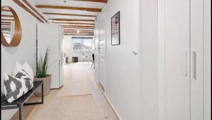 A hallway with a bench, a potted plant, and a door leading to a kitchen area.