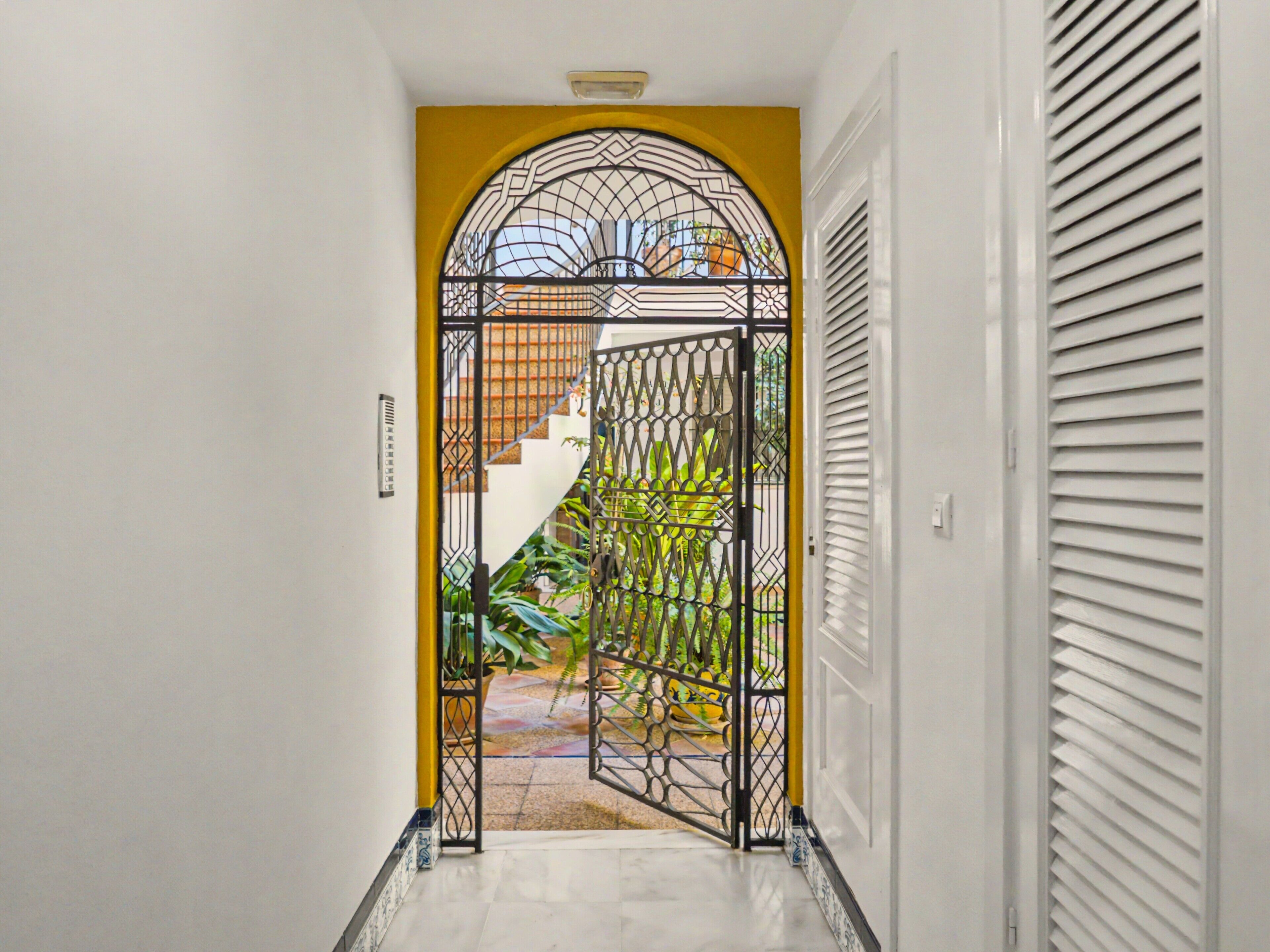 A hallway with a decorative metal gate leading to a staircase.