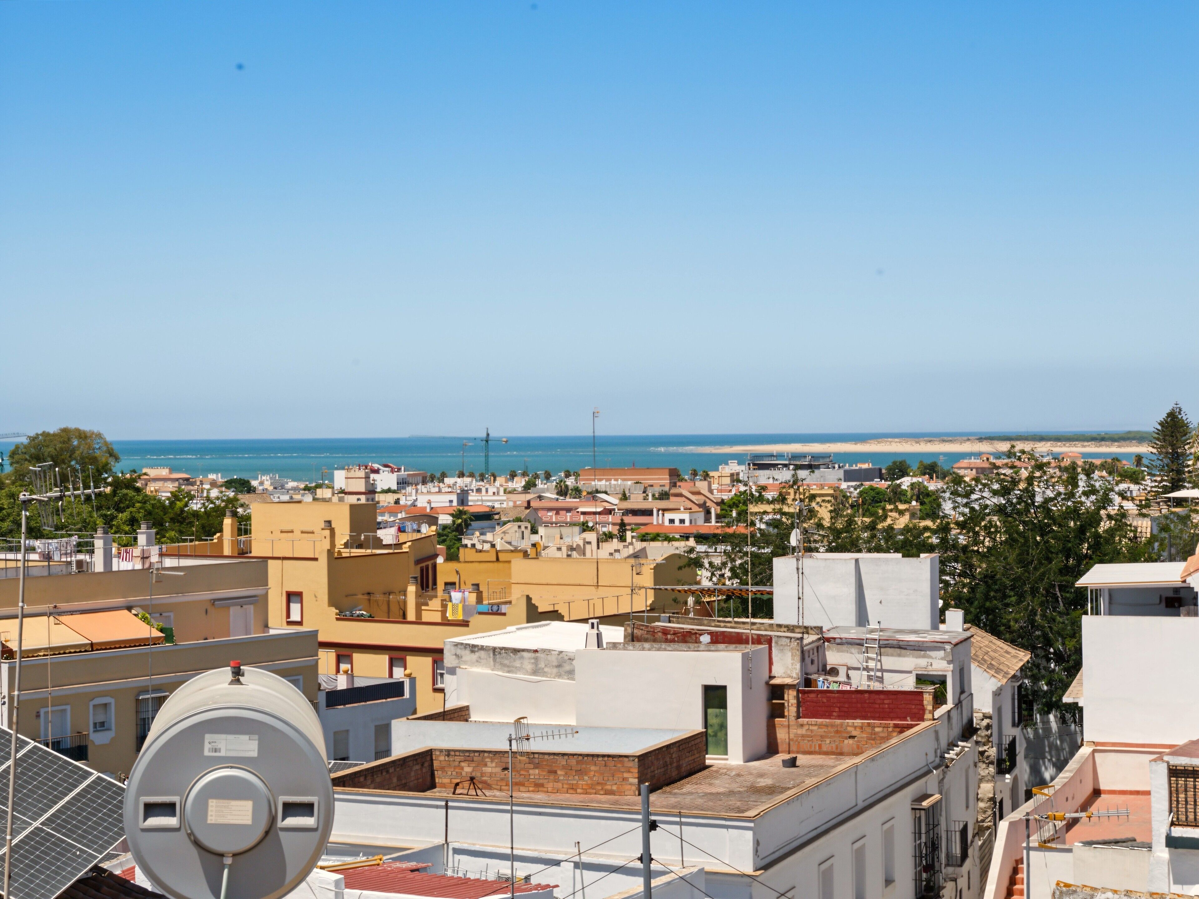 A coastal cityscape with buildings, a clear sky, and a view of the sea.