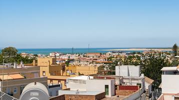 A coastal cityscape with buildings, a clear sky, and a view of the sea.