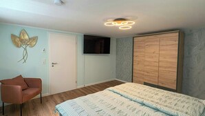 A bedroom with a bed, a chair, a wardrobe, and a television on the wall. - Holiday home on Lake Ternscher with private jetty (Selm)