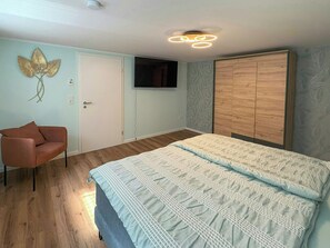 A bedroom with a bed, a chair, a wardrobe, and a television on the wall. - Holiday home on Lake Ternscher with private jetty (Selm)
