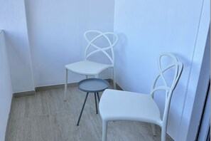 Un petit espace clos comprenant deux chaises blanches et une petite table ronde.