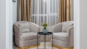 A room with two armchairs, a small table with a plant, and a window with sheer and heavy curtains. - Spacious 3-room apartments (Almaty)