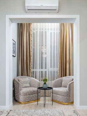 A room with two armchairs, a small table with a plant, and a window with sheer and heavy curtains. - Spacious 3-room apartments (Almaty)