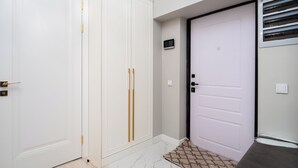 A hallway with white doors, a patterned rug, and a thermostat on the wall. - Spacious 3-room apartments (Almaty)